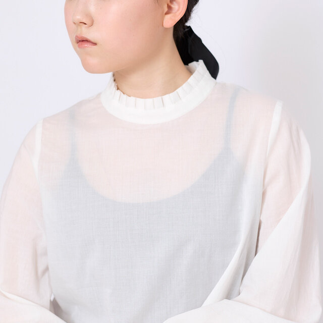 首元を彩る細かなプリーツフリルが、顔まわりに繊細で上品なアクセントを添えます。