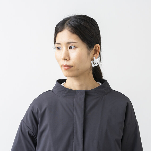 首元はほんのり立ち上がったボトルネック仕様で、女性らしく上品な印象に。
フロントのスナップボタンを1〜2個開けて衿を少し外側に倒せば、表情の異なるVネック風の着こなしが楽しめます。首元にゆとりが生まれるため、ストールやマフラーを巻くときや、タートルネックをのぞかせたい時にも綺麗に決まります。