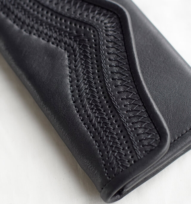 たっぷりと刺繍をあしらったフラップが特徴の長財布。フラップの曲線がフェミニンな仕上がりです。