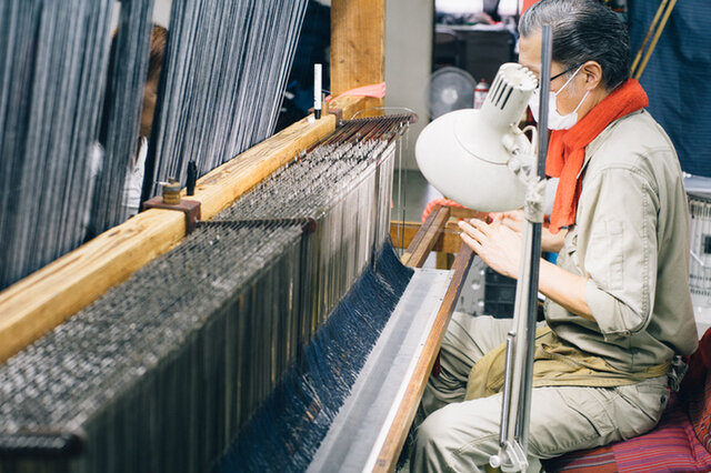 3000本～5000本の糸を2人1組で通していく、経糸の「引き込み」と呼ばれる作業。和木綿に表情をつける大切なひと手間。