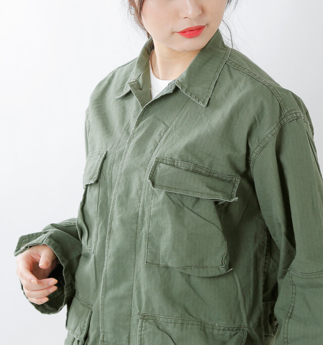 きちんと感のある襟元に、スッキリとした比翼仕立てで、ハードな中に女性らしさも感じられるデザインに仕上げています。きちんと感のある襟と、ひとつだけ表にでた襟もとのボタンがポイントになっています。