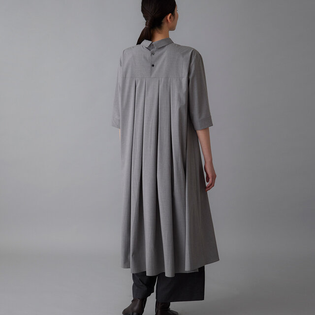 小さな襟と並ぶボタン、流れるようなプリーツが、後ろ姿に静かな可愛らしさを添えます。