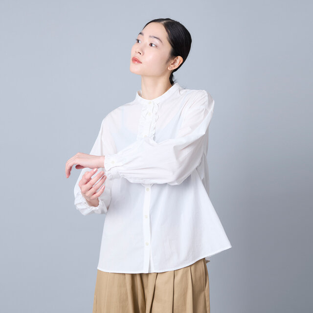 首元をすっきり見せるバンドカラーと前立てのフリルが、顔まわりにさりげない華やかさを添えます。