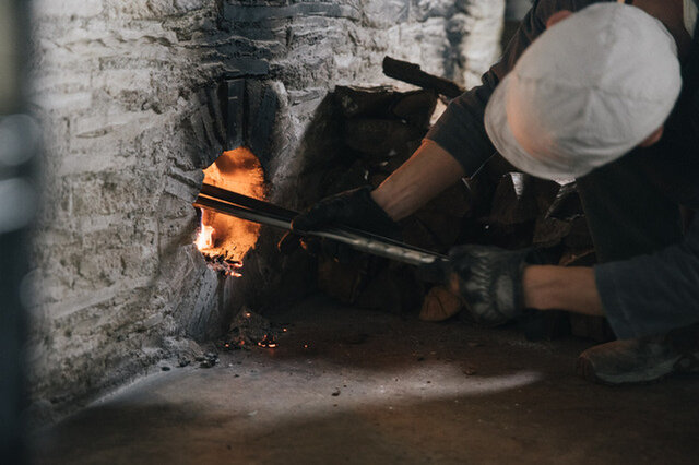 パンの製造作業をしながら薪をくべて、徐々に窯を温める。