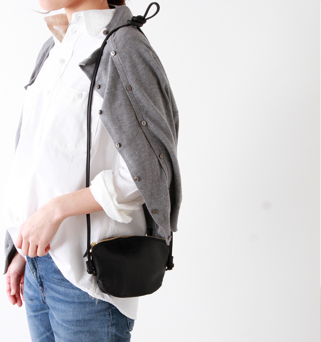 小さなバッグの雰囲気を壊さない華奢なショルダーストラップは、サイドを結んだだけのシンプルな作り。バッグと同じレザーを使用し、華奢ながらしっかりとした使用感です。
また、好みの長さで自由に長さ調節ができ、ストラップを外せばポーチとしても使用できる2way仕様。コスメポーチや貴重品入れとして、毎日使うバッグの中に入れていてもコンパクトなので荷物になりません。
